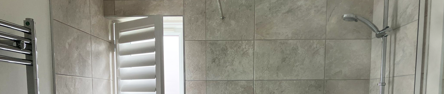 A bathroom shower alongside open shutters